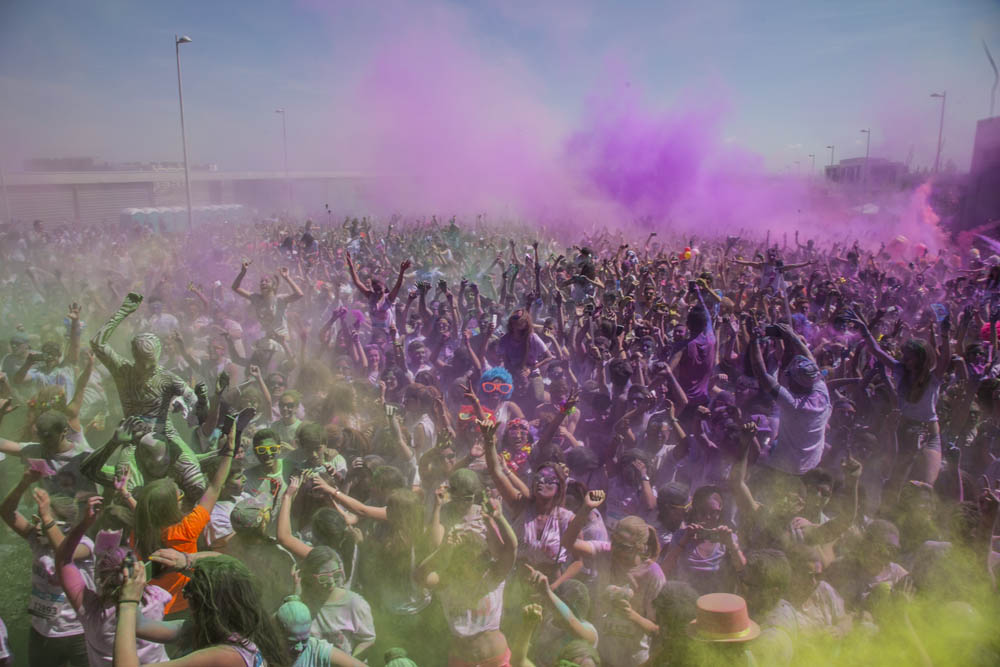 Multitud celebrando la carrera Holi con explosiones de color